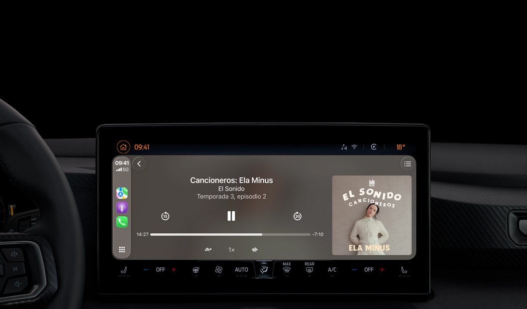 Interior de un auto, la pantalla de la consola central muestra Apple Podcasts reproduciéndose a través de CarPlay con el podcast "Cancioneros: Ela Minus" de El Sonido, aparecen los controles de reproducción para retroceder, pausar y avanzar.