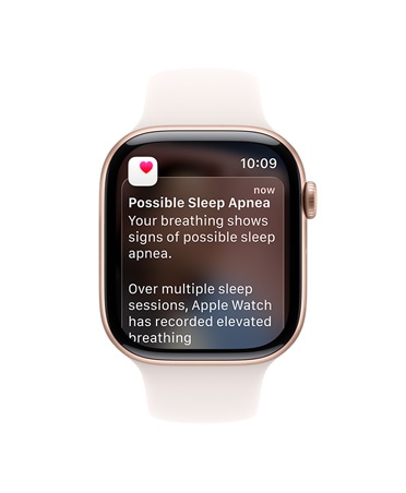 Apple Watch Series 11, růžově zlatá barva, hliníkové pouzdro, rozbalené oznámení o spánkové apnoi, na pravém boku korunka Digital Crown, sportovní řemínek, světle ruměná barva