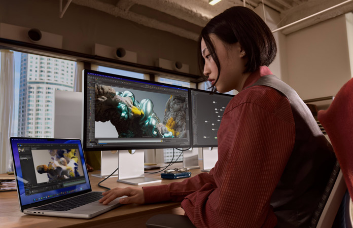 Una persona trabaja en una oficina con un MacBook Pro conectado a un Studio Display XDR
