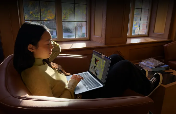 A person sitting in a chair using their MacBook Air