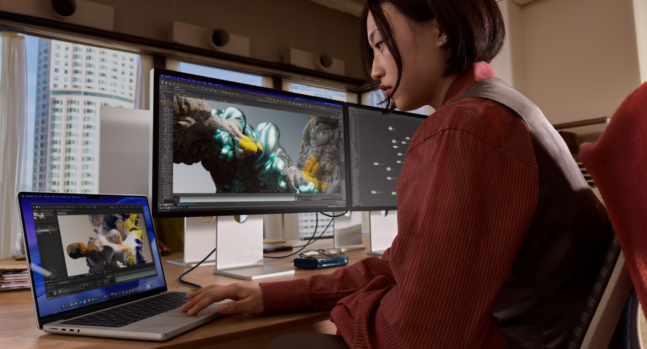 Egy ember irodai környezetben MacBook laptopon dolgozik, amelyhez Thunderbolt 5 porton keresztül egy Studio Display XDR van csatlakoztatva