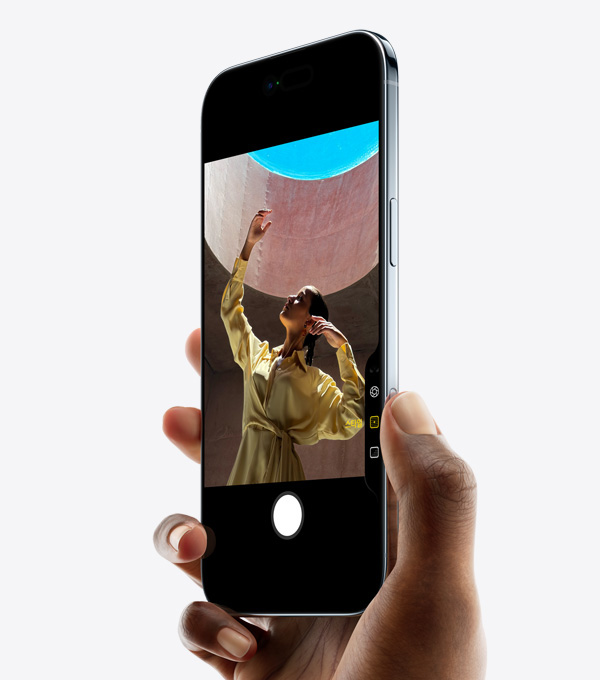 한 손으로 iPhone Air를 든 채 엄지를 카메라 컨트롤 버튼에 대고 있는 모습. 기기 앞면과 옆면, 얇은 두께, Dynamic Island, 측면 버튼이 보입니다