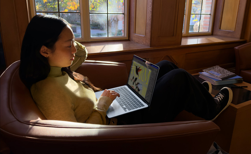 Une personne assise dans un fauteuil utilise son MacBook Air