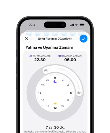 iPhone, Uyku programına açık Sağlık uygulaması, yatma saati 22:30 olarak ayarlanmış, uyuma saati 6:00 olarak ayarlanmış, merkez ekranda radyal zaman kadranı, 7 saat 30 dakika uyku hedefi karşılandı Bir kişi iPhone'da olası uyku apnesi uyarısının ayrıntılarını kontrol eder