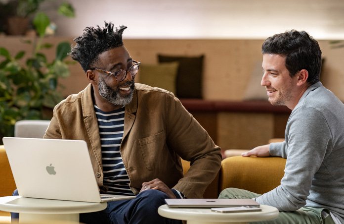 MacBook abierta sobre una mesa delante de una persona sonriendo