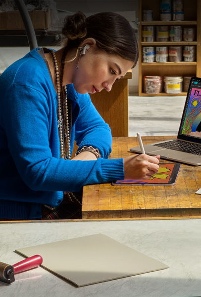 兩位學生在宿舍房間內使用銀色 MacBook 瀏覽內容，一位坐在床上，另一位則坐在地板上手持裝置