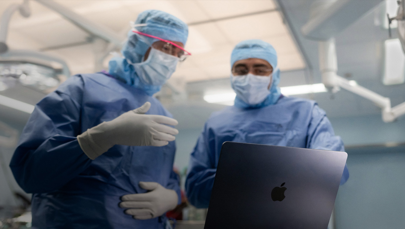 手術室でMacBook Proの画面を見ながら話し合う2人の外科医
