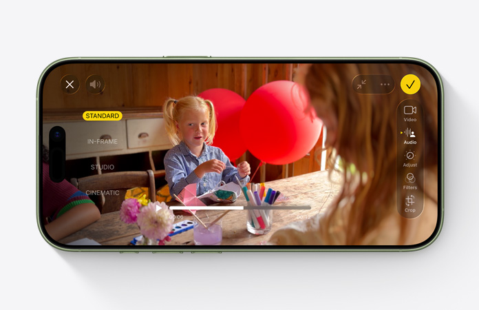 iPhone 17 vist forfra, video med Lydmiks-funktionen i brug, hvor et barn leger ved et bord med balloner