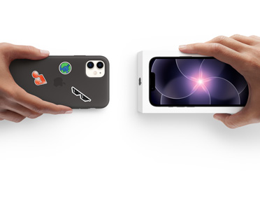 Dos manos intercambian un iPhone 13 con carcasa de silicona y stickers en la parte trasera por un nuevo iPhone 17 Pro en su caja.